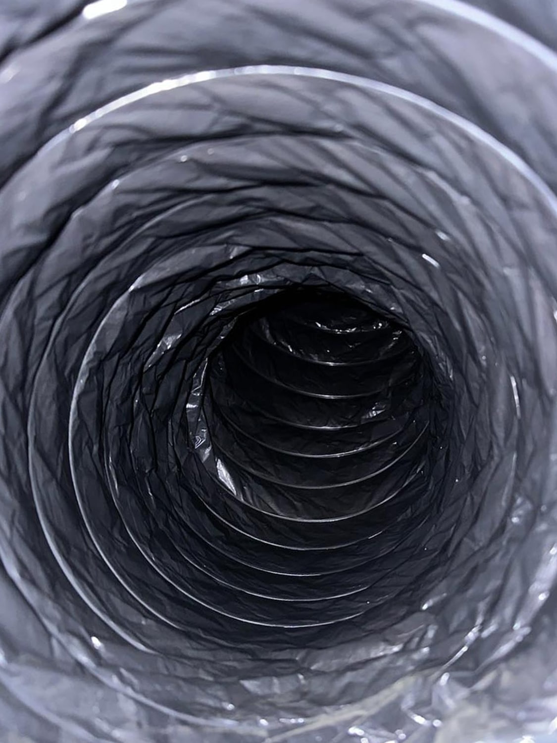 Close-up view of a black flexible duct, showcasing the interior spiral structure, relevant to 800 Duct's air duct cleaning services.