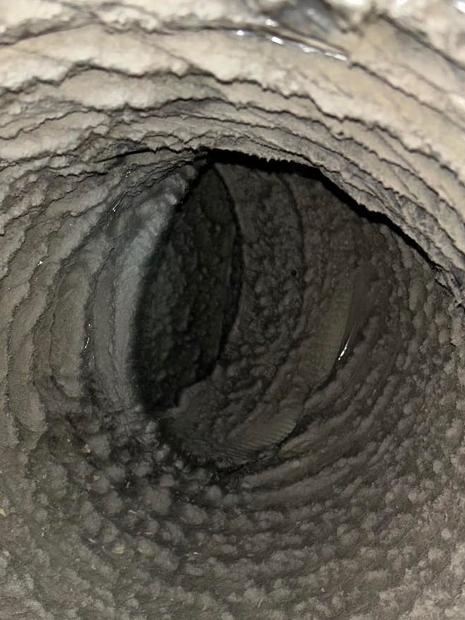 Close-up view of a dirty air duct interior, showing thick layers of dust and debris, illustrating the need for duct cleaning services by 800 Duct.