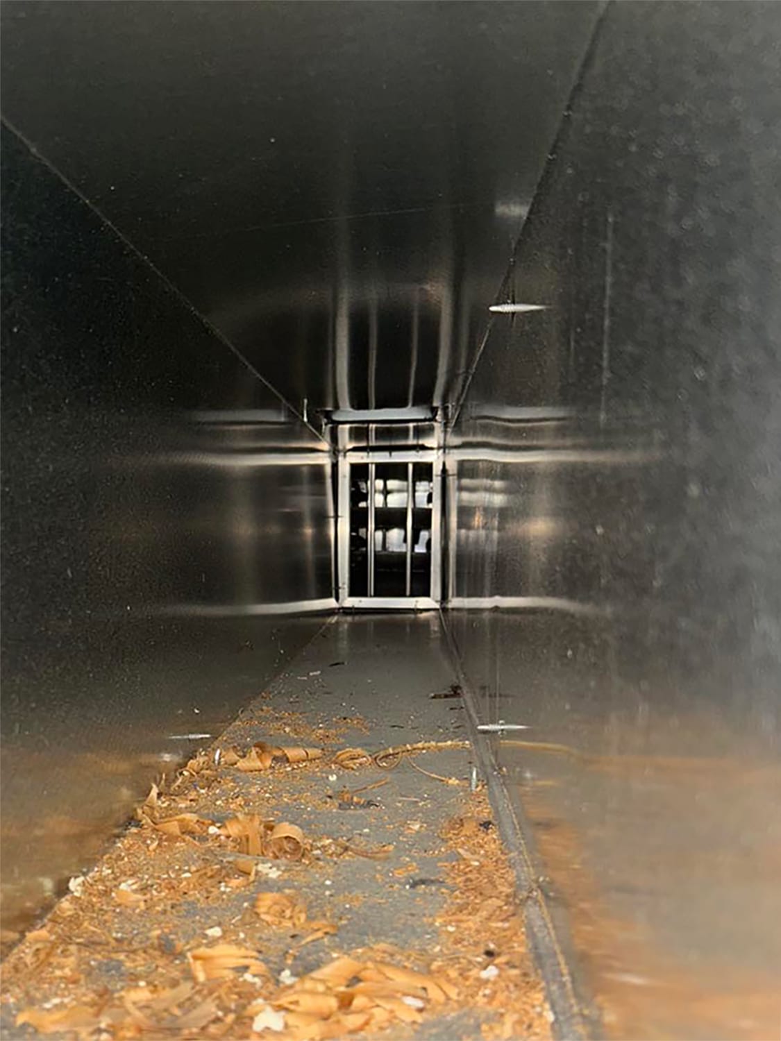 Interior view of a duct showing debris and dust on the floor, illustrating the need for duct cleaning services by 800 Duct.